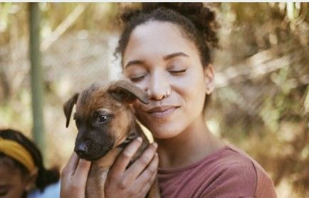 A young woman cuddling a puppy